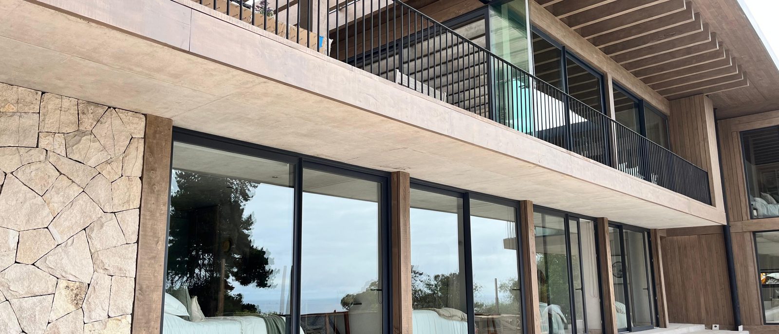 Fachada con revestimiento de piedra, madera y vidrio, vista con dron